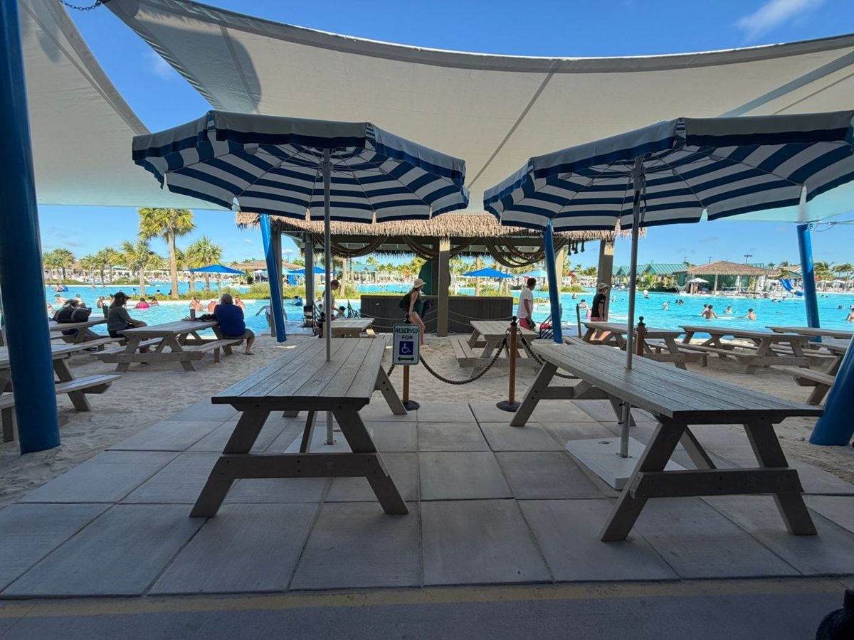 Shaded picnic tables on a paved pad at Captain's Galley, with a sign reserving them for wheelchair users, overlooking Starfish Lagoon