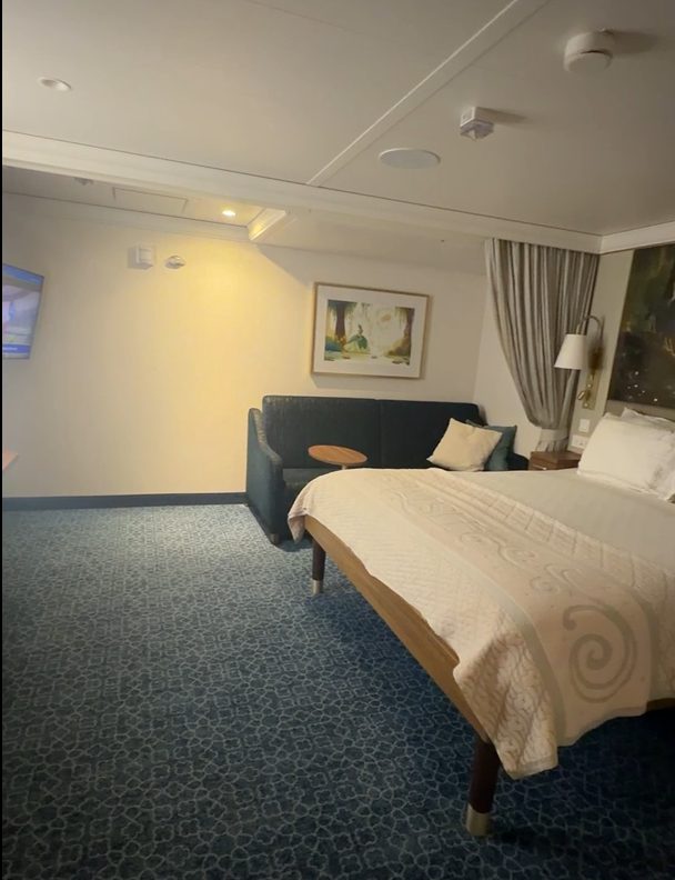 Interior of a Disney Cruise Line accessible stateroom, showing the bed, sitting area, and open floor space for maneuvering a wheelchair