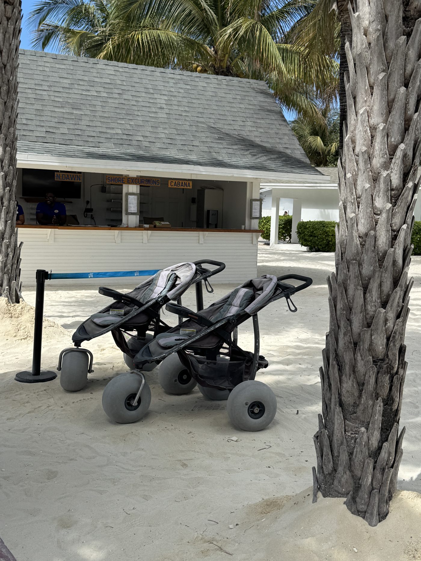 Beach strollers with large balloon tires parked near the Shore Excursions cabana at Great Stirrup Cay