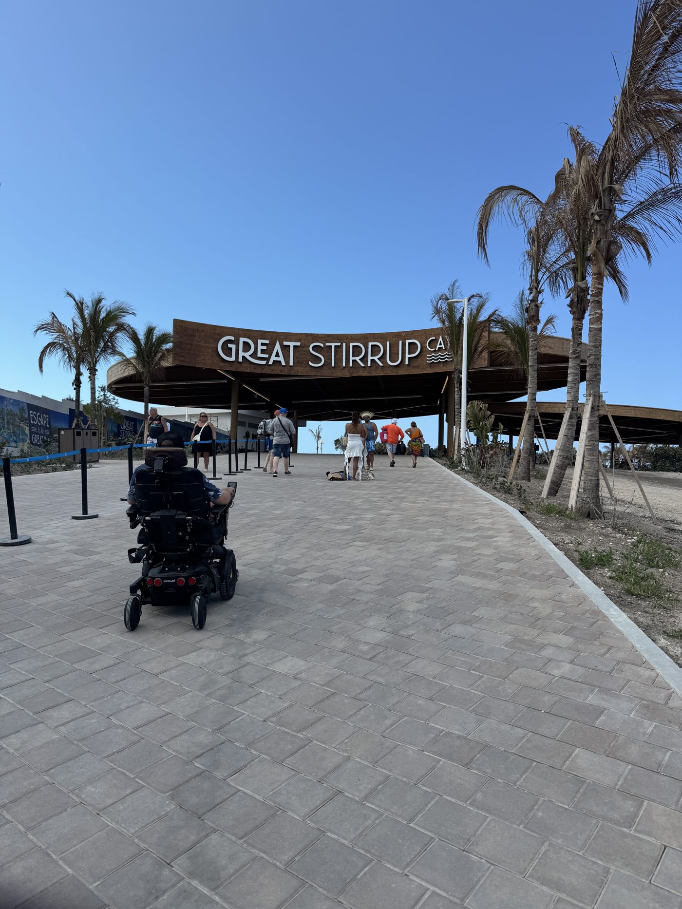 A traveler using a power wheelchair on the paved walkway leading from the pier to the Great Stirrup Cay entrance